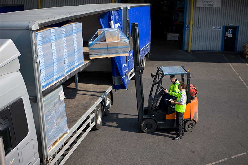 A warehouse team member pushing a roll cage.