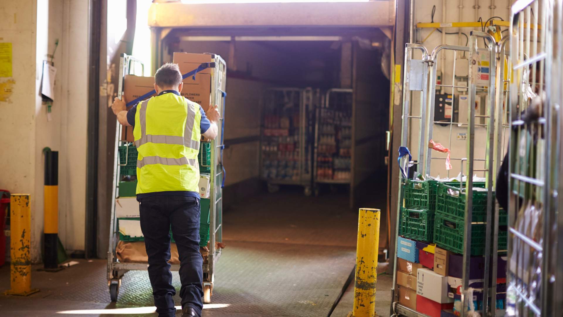 A warehouse team member pushing a roll cage.