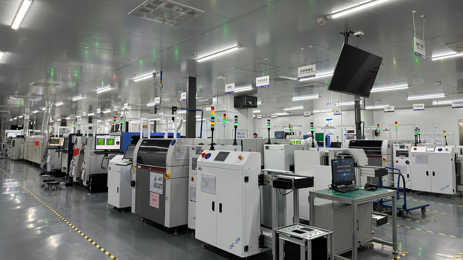 A white factory interior containing a range of industrial equipment and screens.
