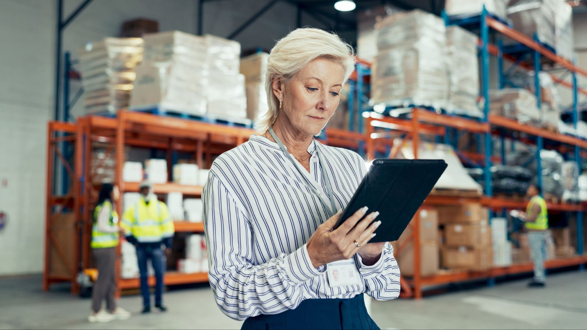 Supply-Chain- Work A smartly-dressed logistics professional using a tablet in a warehouse. s