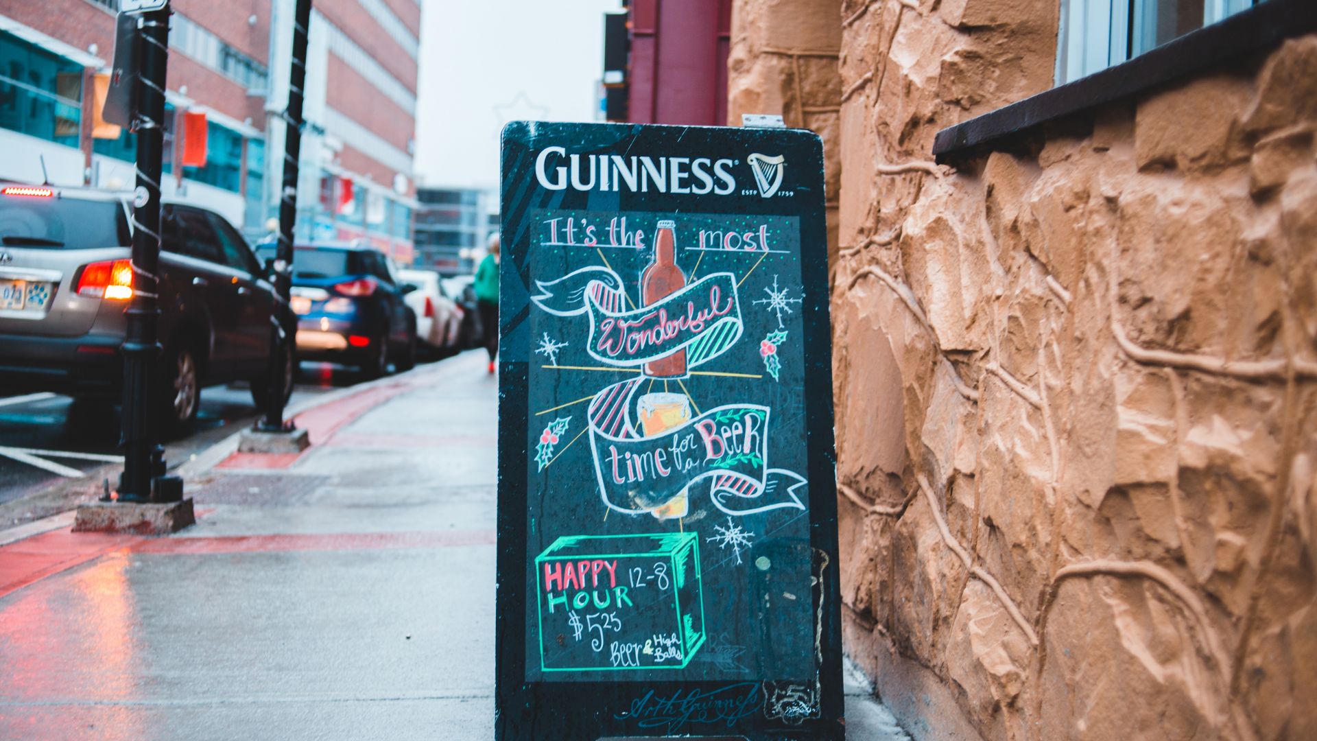 A sign outside a pub showing Guinness and advertising a ‘happy hour’. 
