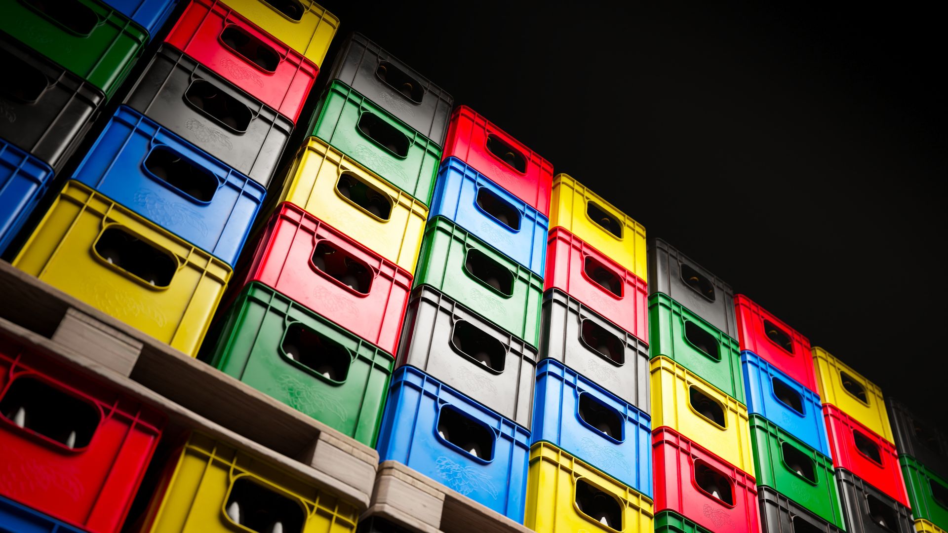 Blue, grey, green, red and yellow reusable plastic crates stacked high.